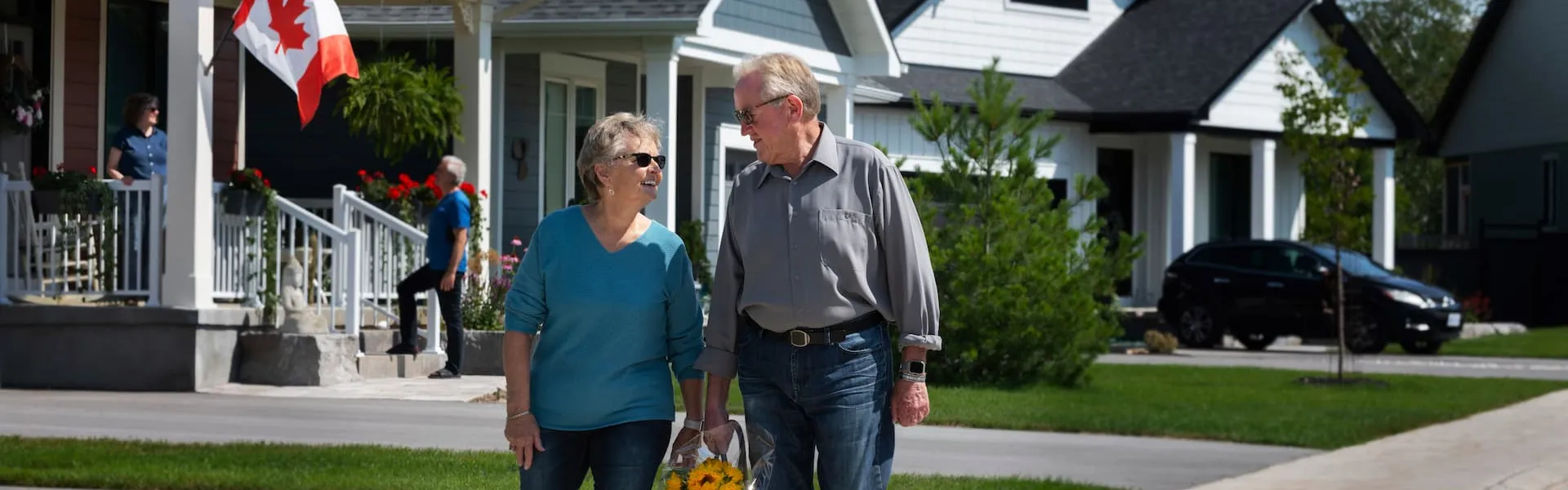 Two Watercolour residents holding a bag of flowers together, walking down the street.