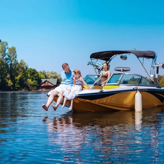 Happy together. Caring young father and his little daughter sitting on the bow of the boat together while the mother observing them fondly