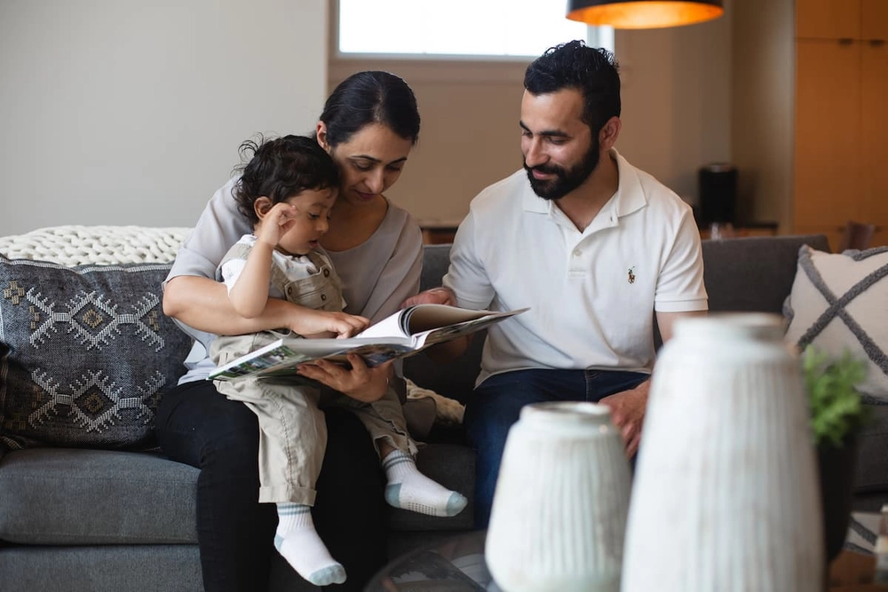 A young family reading a book with their child.