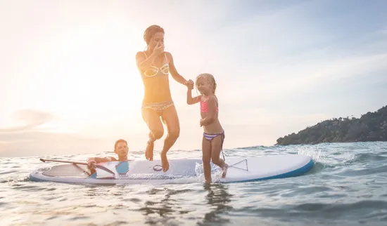 A mother and her young daughter jumping off a paddle board into the Upper Rideau Lake.