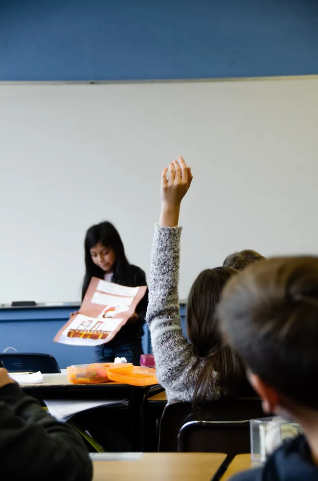 A gilr asking a question in class.