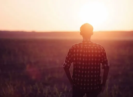 A man looking off into the sunset.